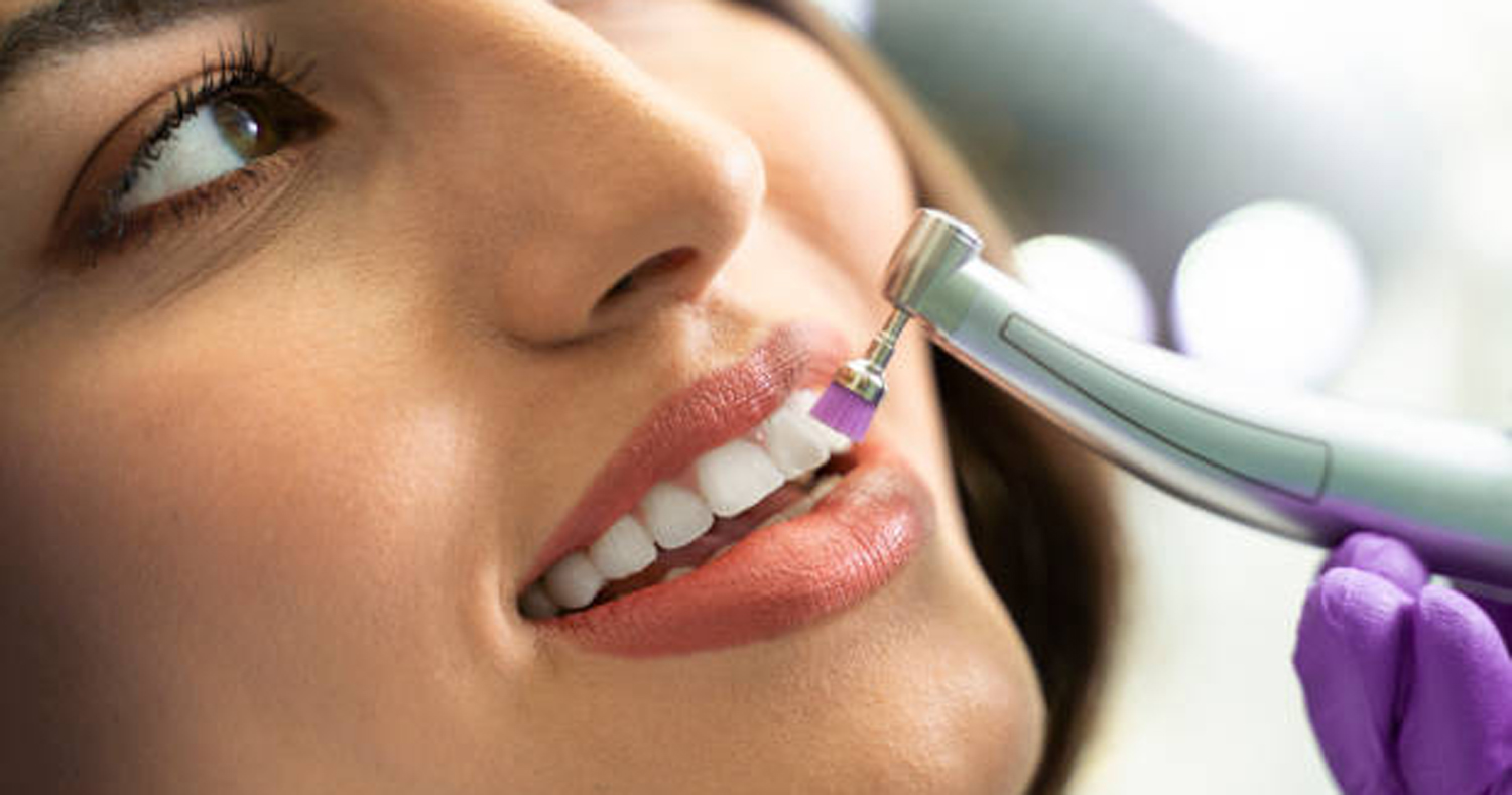 Closeup young woman getting her teeth polished bright background